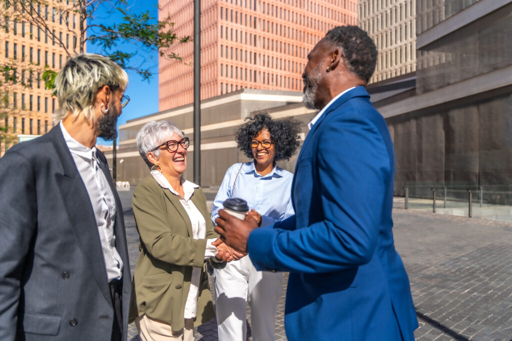 Four diverse professionals having a lively conversation outdoors in a city setting.