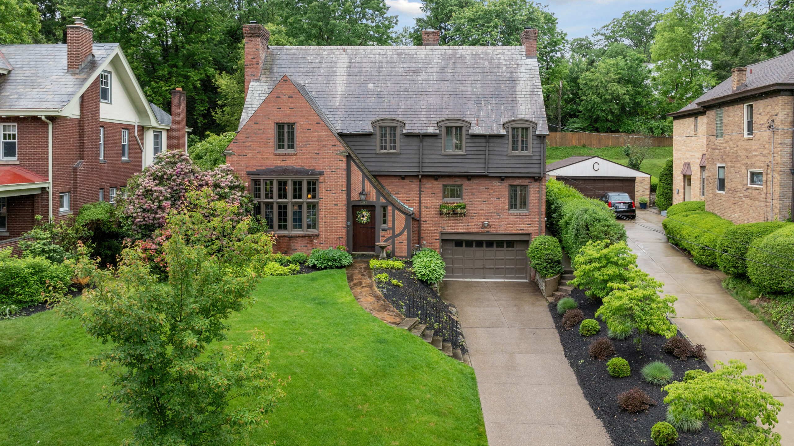 Charming brick house with a neatly manicured lawn and driveway.