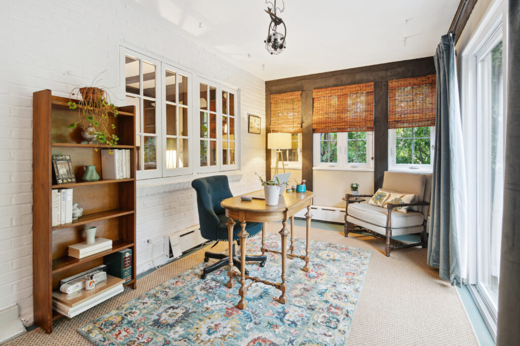 Cozy home office with wooden desk, cushioned seating, and patterned rug.