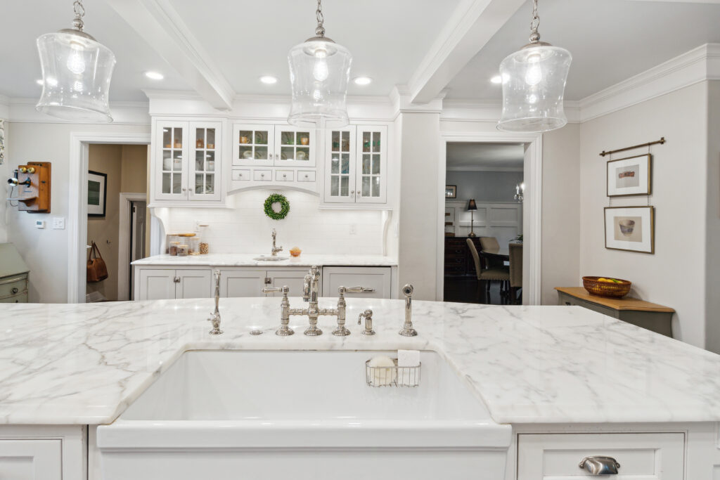 Bright white kitchen with marble countertops and modern lighting.