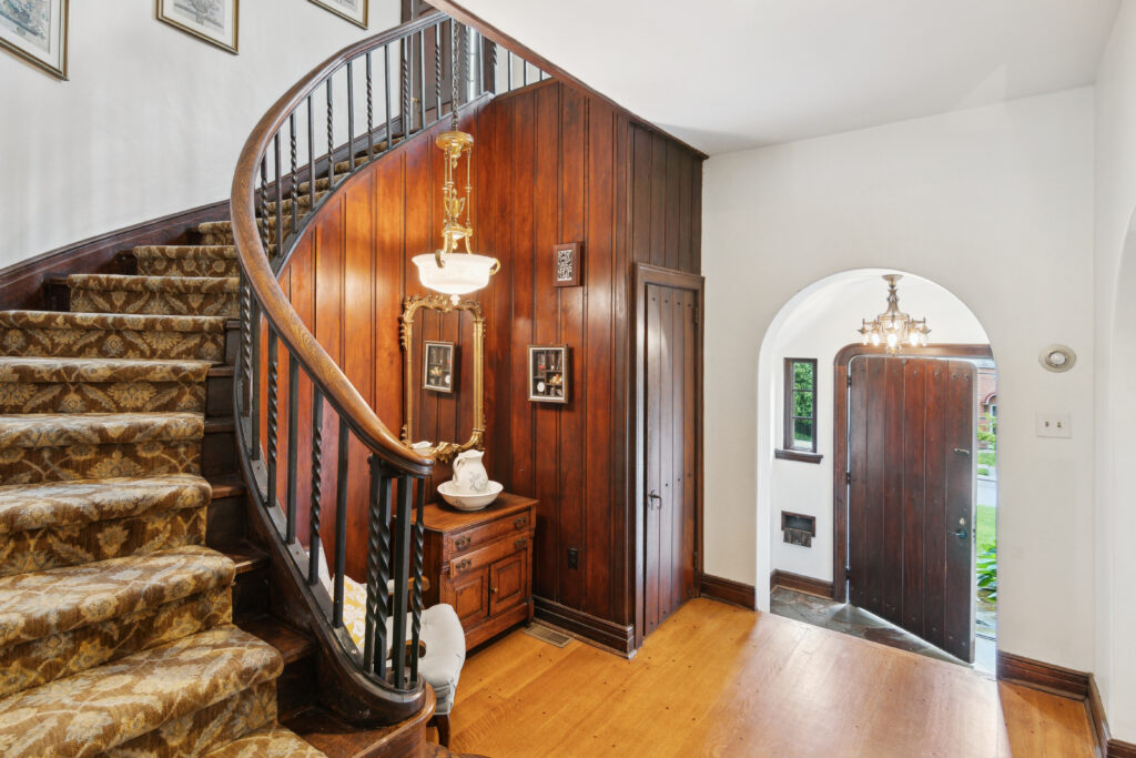 Elegant wooden spiral staircase with classic decor in a cozy home entryway.