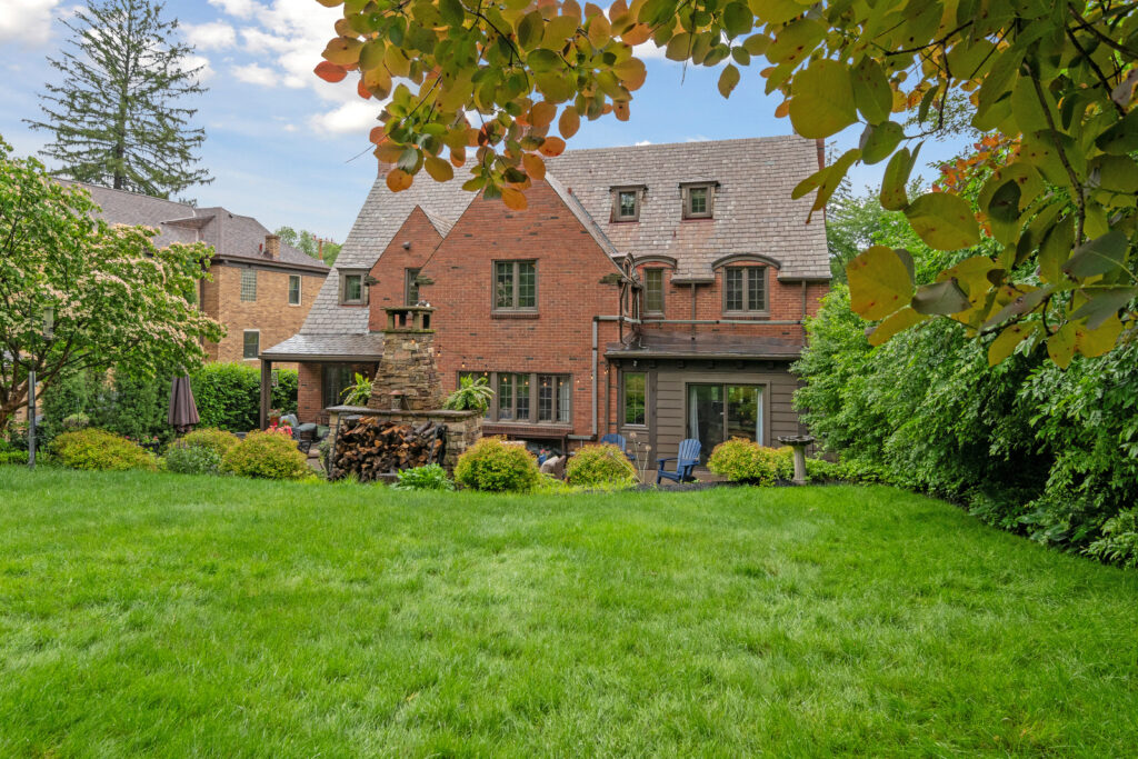 Large brick house with a spacious green lawn and outdoor seating area.