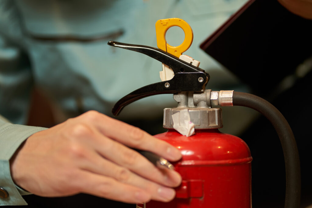 Hand adjusting the valve on a red fire extinguisher.