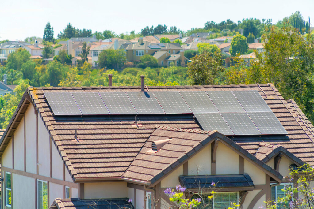 Suburban houses with tiled roofs and greenery in the background.
