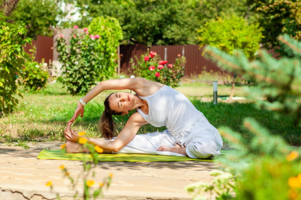 Woman practicing yoga outdoors in a serene garden setting.