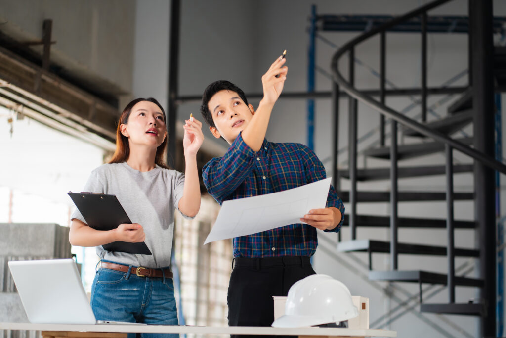 Two architects discuss plans at a construction site.