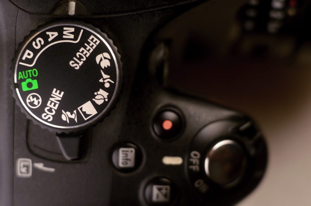 Close-up of a camera mode dial and buttons in low light.