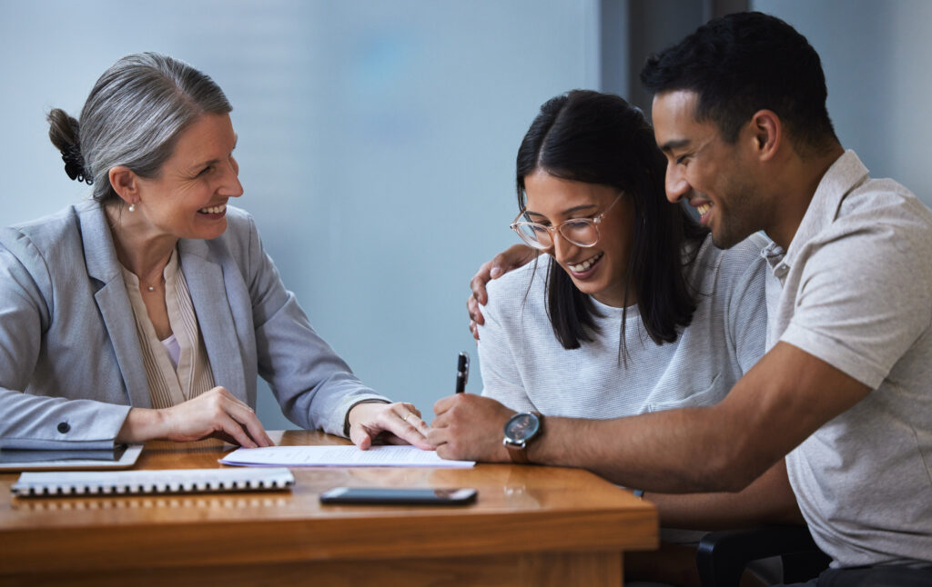 Three people collaborating happily around a table with documents.