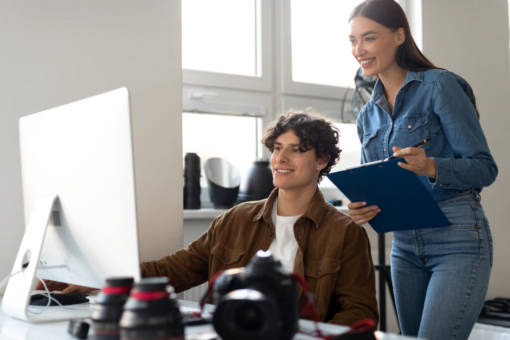 Two photographers reviewing images on a computer in a studio.