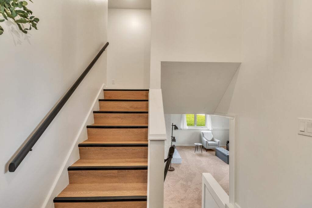 Modern staircase with wooden steps and a cozy landing area below.
