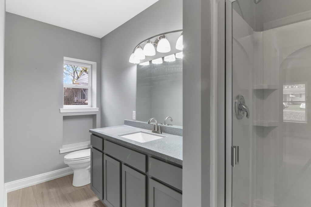 Modern bathroom with gray cabinetry and a large mirror.