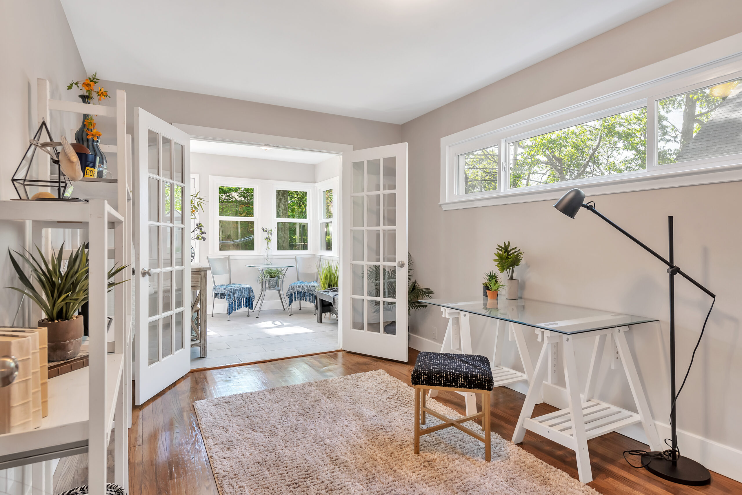 Bright home office with glass doors opening to a sunlit sitting area.