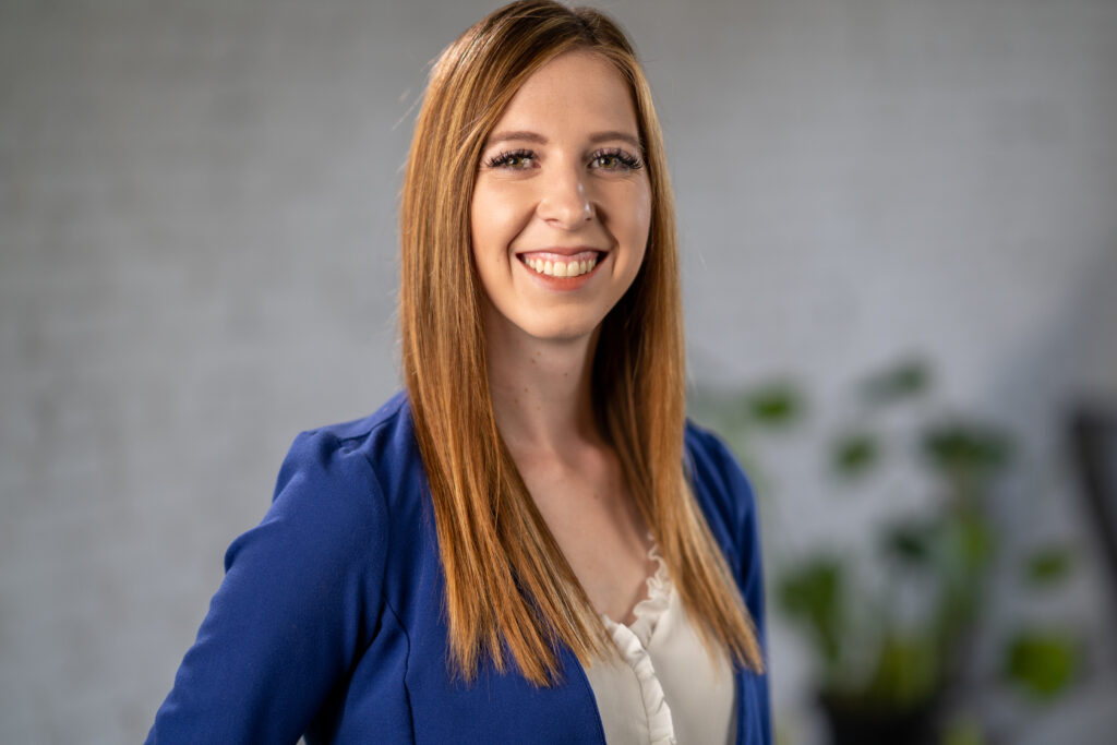Professional woman with long red hair smiling confidently at the camera.