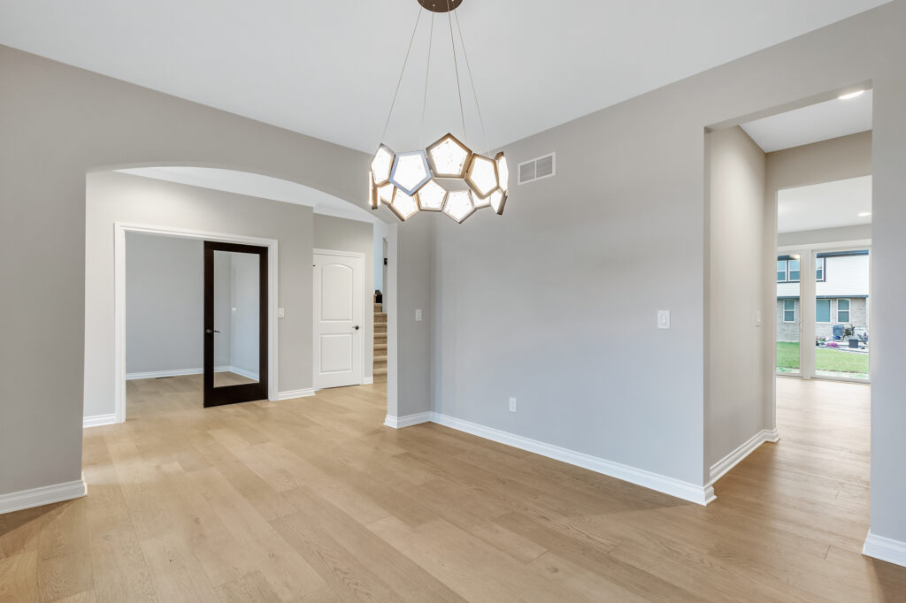 Modern empty room with wooden flooring and unique chandelier lighting.