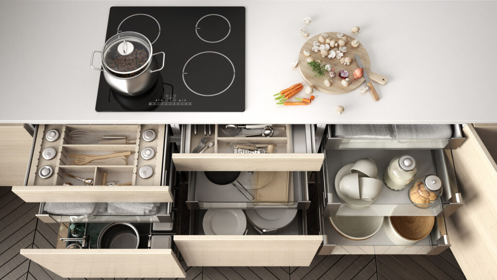 Organized kitchen drawers with neatly arranged utensils, pots, and pans.