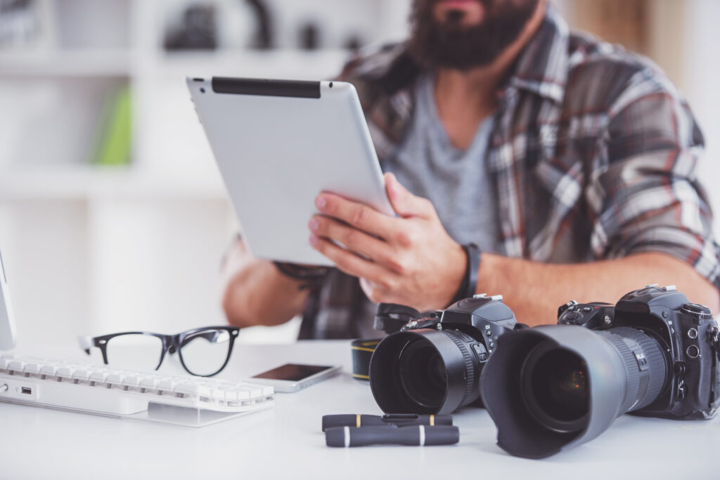 Man holding a tablet with camera gear on a desk.