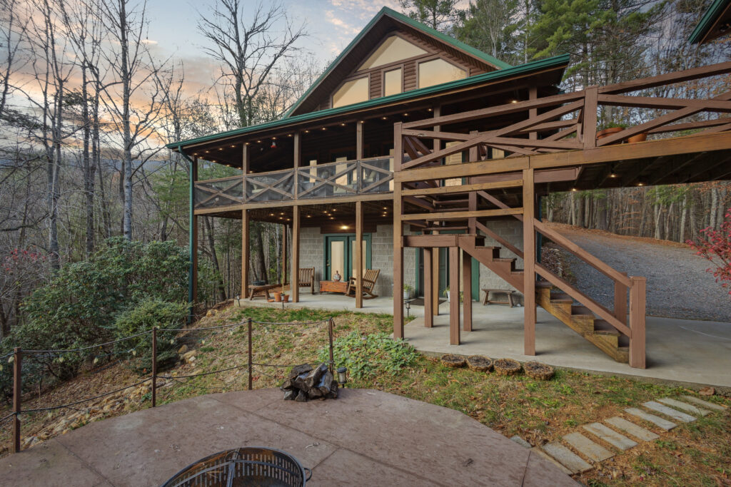 Cozy multi-level wooden cabin surrounded by trees at sunset.