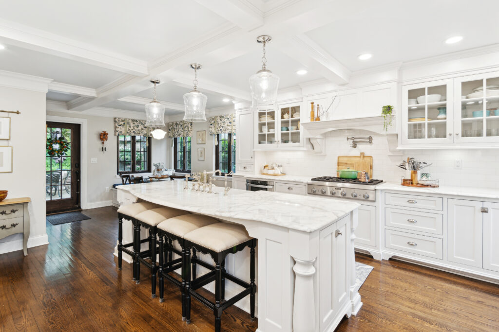 Spacious white kitchen with a large marble island and dark wooden stools.