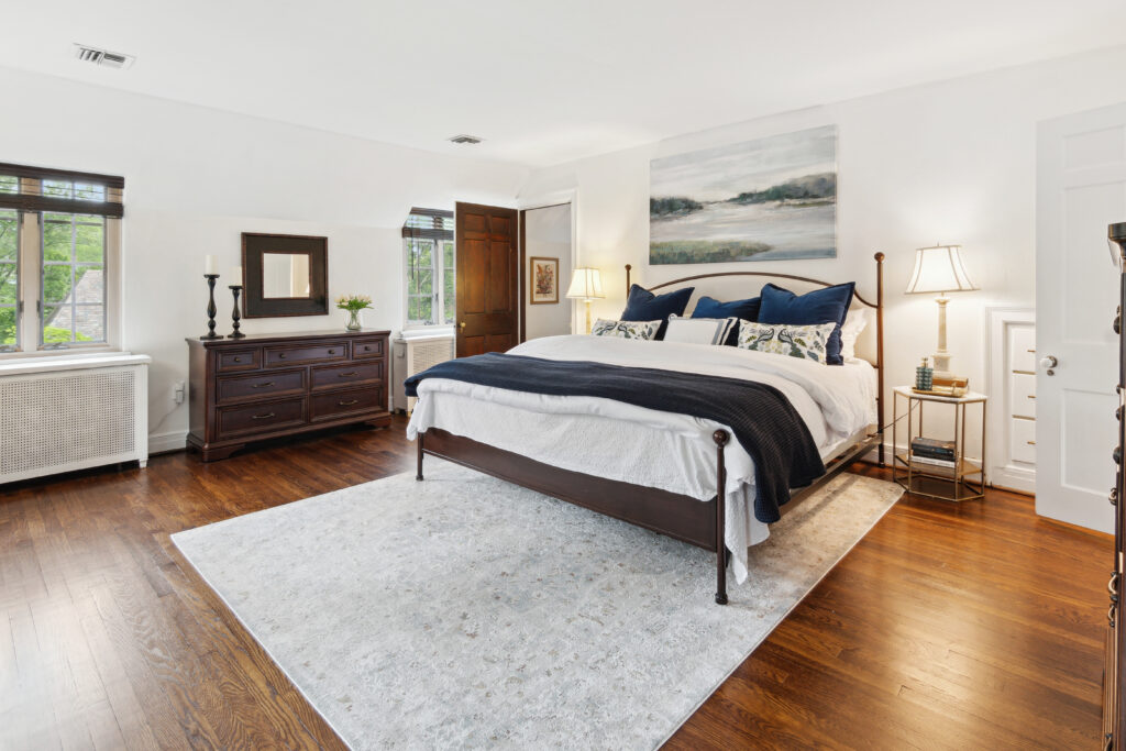 Modern bedroom with a wooden bed frame, blue bedding, and a large area rug.
