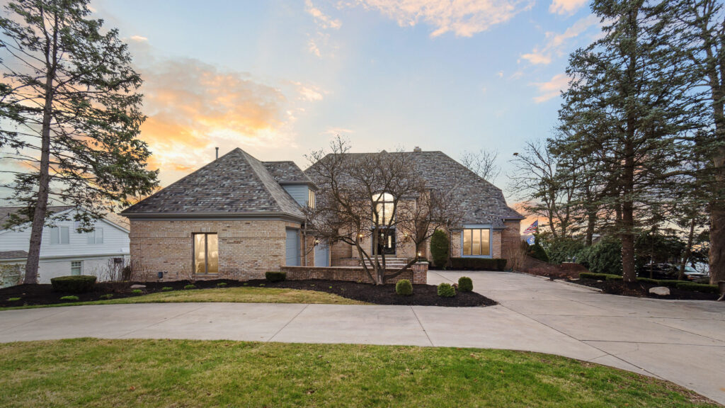 Elegant stone house with a driveway at sunset.